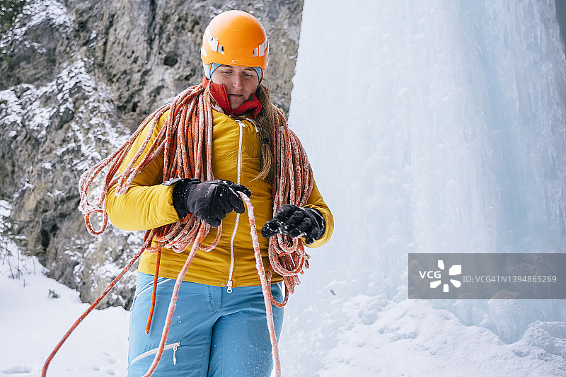 寒冷的一天，一名妇女在加拿大落基山脉攀冰时盘着一根绳子图片素材