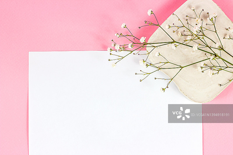 白色空白笔记本页的副本空间的文本与小花在粉彩粉红色的背景俯视图。空的结婚用纸模型，浪漫的情人节信模板图片素材