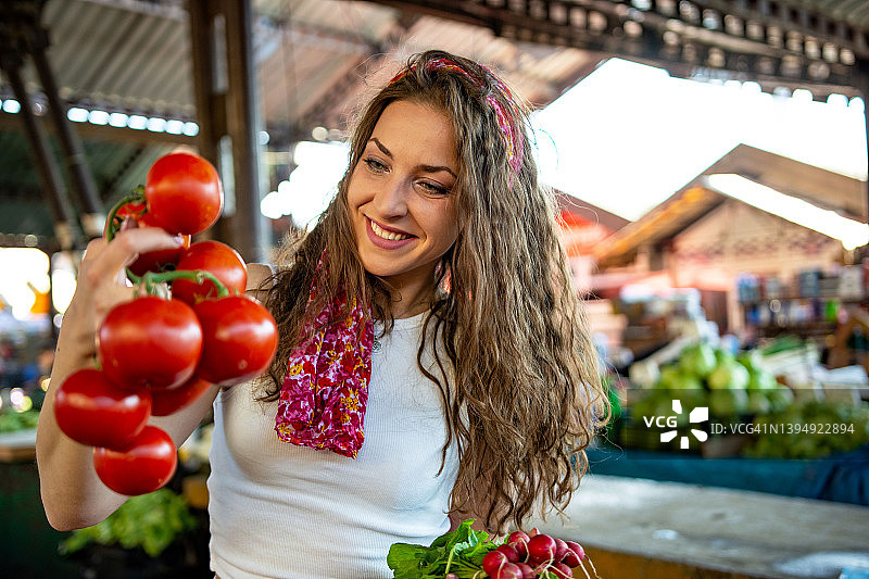 年轻漂亮的女人在市场买菜图片素材