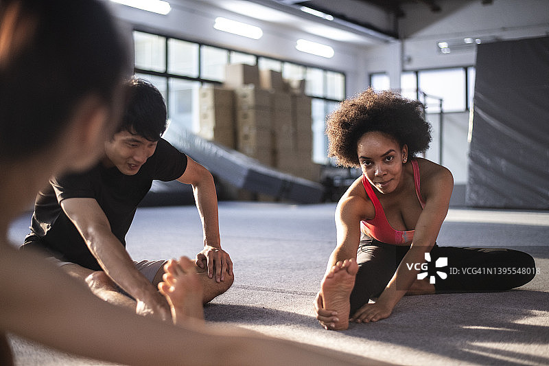 非裔美国女人和亚洲朋友在健身房做伸展运动图片素材