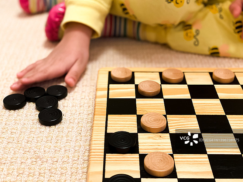 年轻的混血女孩在家里玩跳棋图片素材