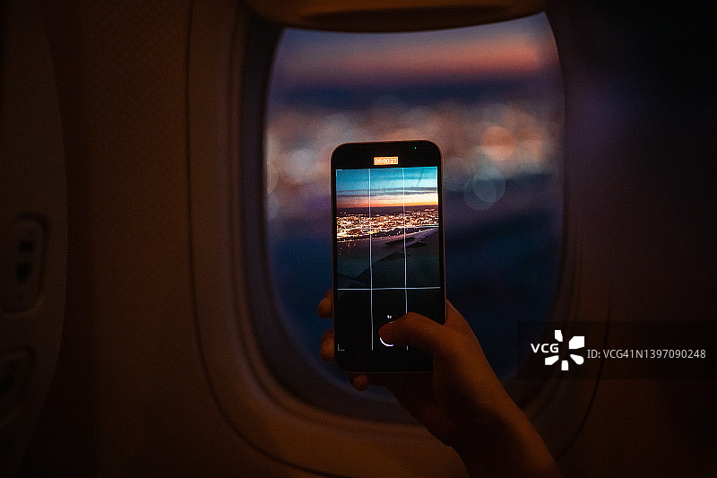 乘客用智能手机通过飞机窗户拍风景照片图片素材