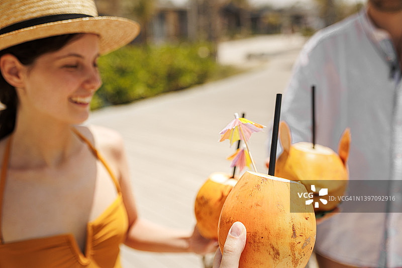 快乐的游客朋友在海滩小摊酒吧用椰子鸡尾酒欢呼-年轻人享受暑假的乐趣图片素材