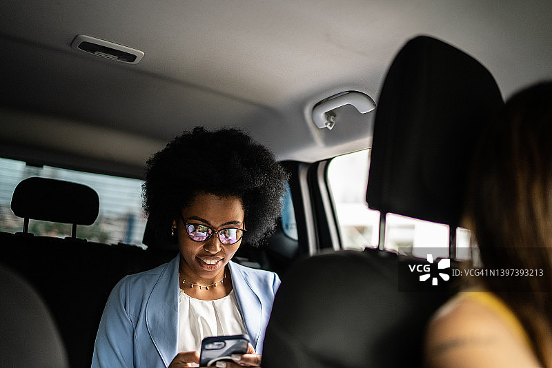 女商人在出租车上使用智能手机图片素材