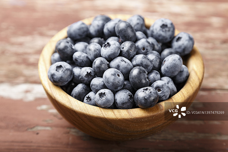 蓝莓放在木制背景的木制盘子里。健康的食物和健康的生活方式。图片素材