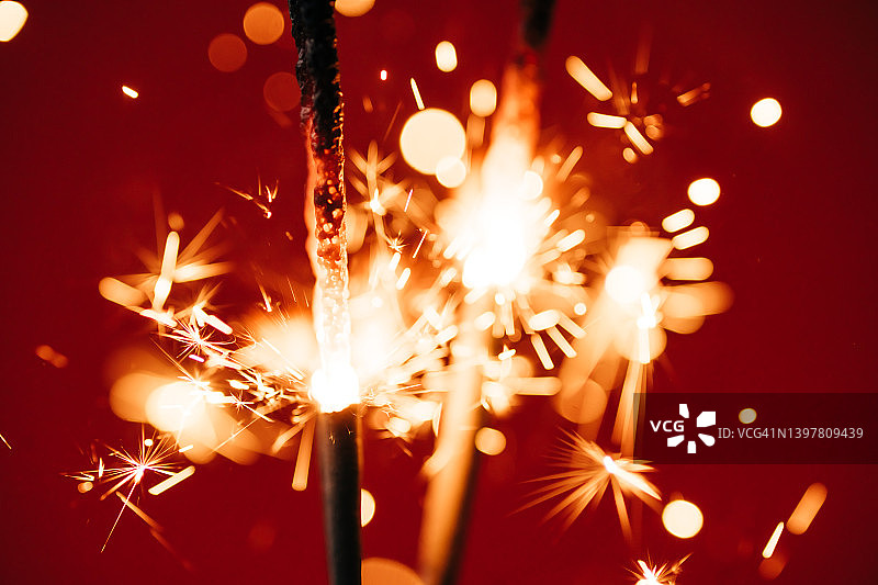 燃烧的火花与许多美丽的火花在红色的背景。新年或生日庆祝的概念图片素材