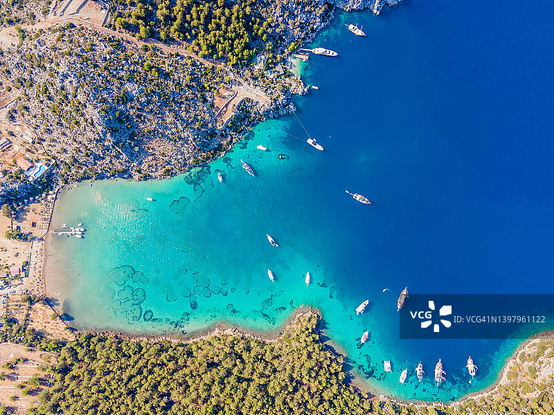 无人机拍摄的每日游船和私人游艇停泊在Cennet湾，位于土耳其Muğla市Marmaris区Selimiye村。图片素材