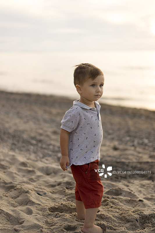 可爱的小男孩站在海滩上图片素材
