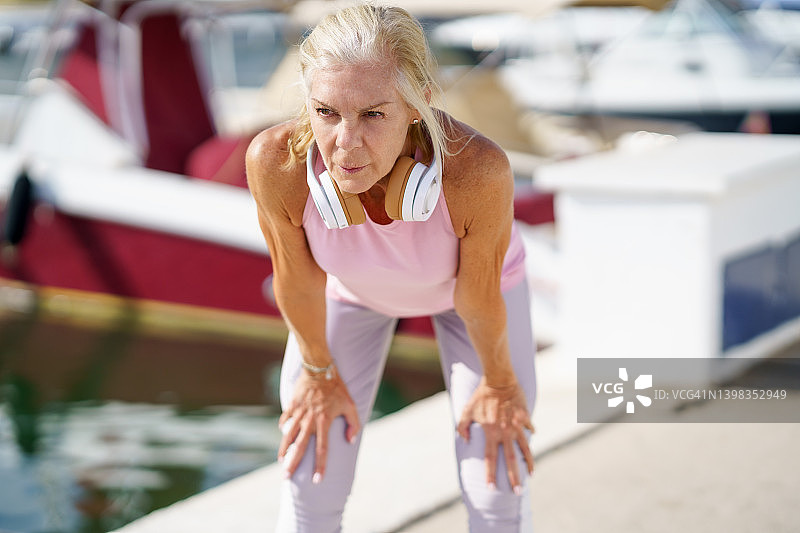 穿着健身服的老年妇女在运动后伸展手臂。图片素材