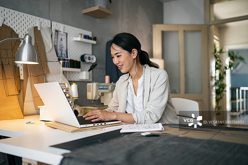 日本裔女性小企业主在设计工作室的笔记本电脑上工作图片素材