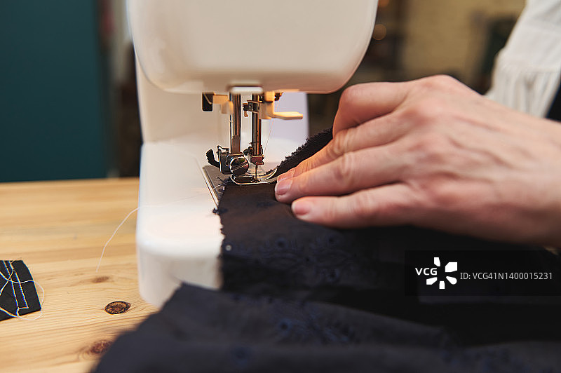 在缝纫机上手工制作新衣服时，女人的手在缝纫的特写图片素材