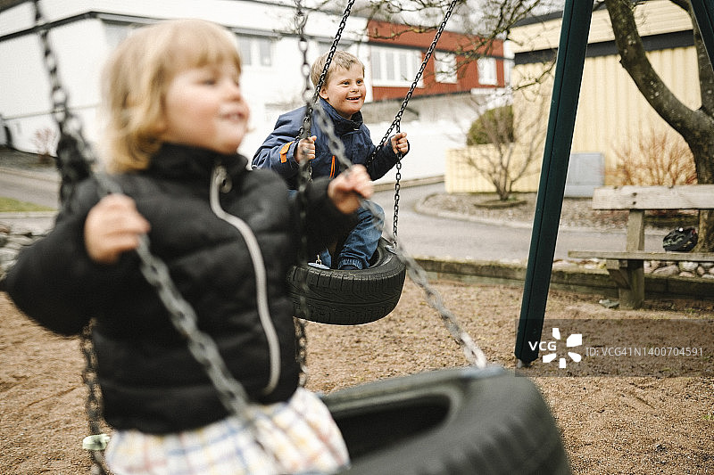 顽皮的弟弟和妹妹在公园玩轮胎秋千图片素材