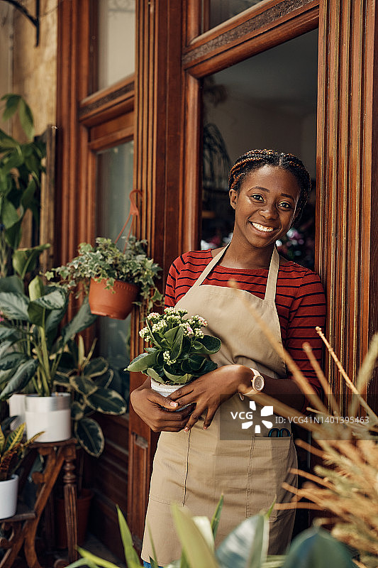 快乐的非洲裔美国女花店门口看着相机。图片素材