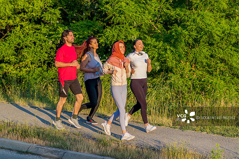 一群健康的人在城市公园慢跑，跑步团队在晨练。一群年轻人在公园里训练图片素材