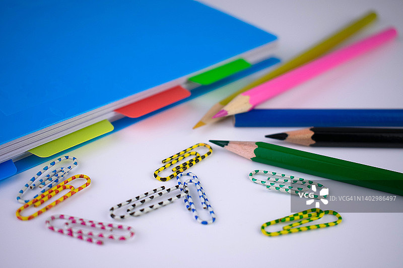 用学校用品回归学校概念。蓝色的记事本，铅笔和回形针。图片素材