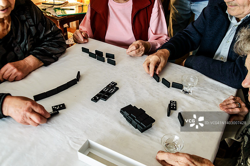 一群老年人通过玩多米诺骨牌来参加一项社交活动。图片素材