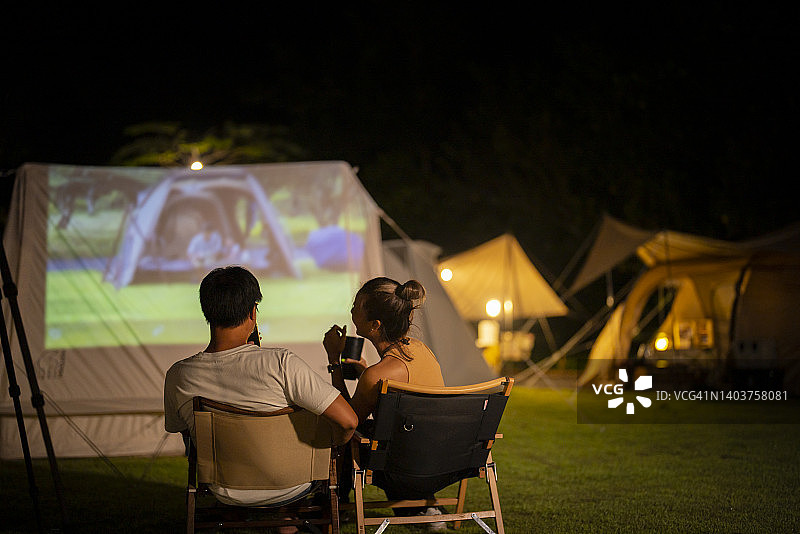 快乐的情侣在营地看电影图片素材