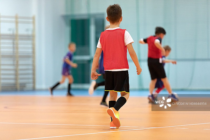 儿童足球训练。室内足球在体育馆里拿着足球的年轻球员。运动背景。小学生踢室内足球图片素材