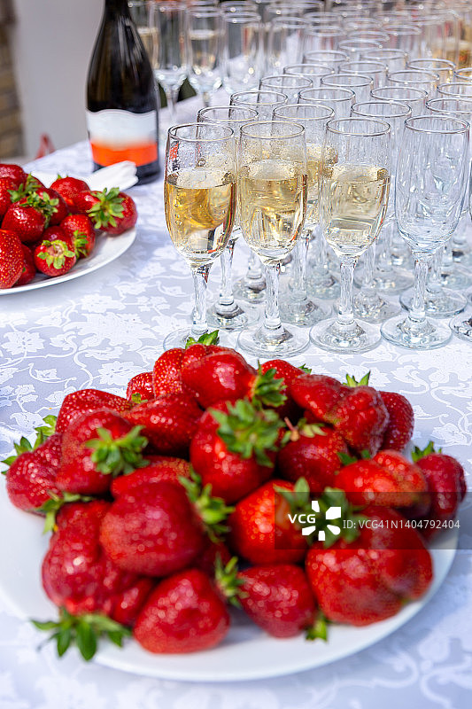 宴会桌上有酒杯和盛着草莓的盘子。图片素材