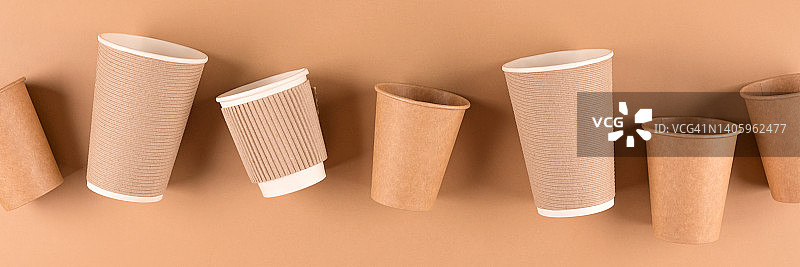 横幅与各种纸咖啡杯在浅棕色的背景。外带热饮的生态纸杯。可持续的外卖食品包装概念。俯视图图片素材