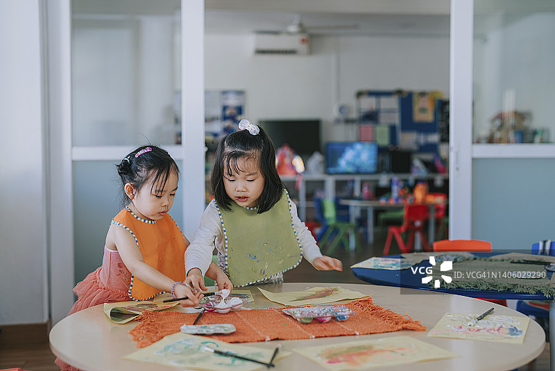 2名亚洲华人蒙氏学龄前女孩喜欢在教室里画画图片素材