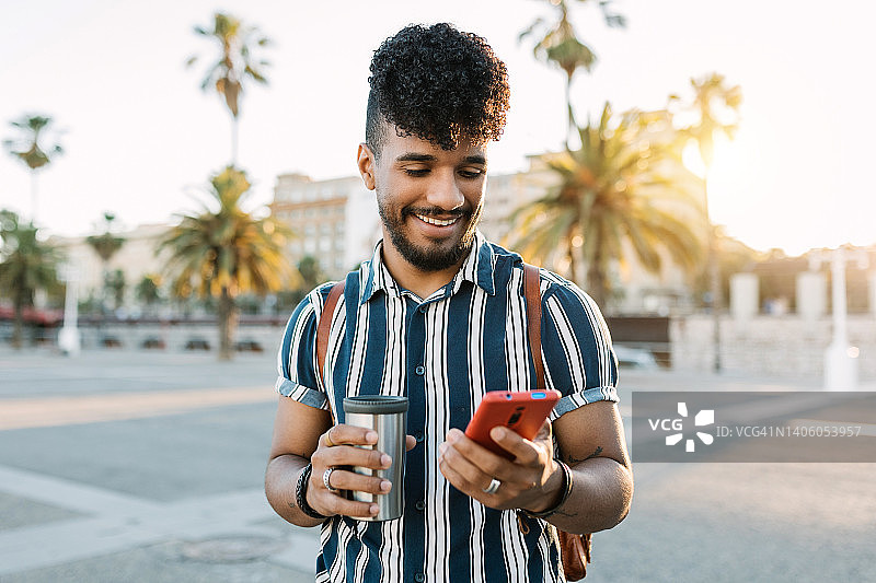 快乐的男人在户外的城市街道上用智能手机看社交媒体内容图片素材