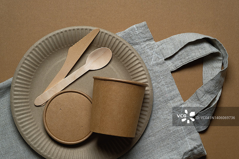 可生物降解的一次性餐具，由可回收的塑料和纸制成，白色背景或桌子。保护、关爱、环保的理念。没有塑料的生活。一个购物袋，一个用回收材料制成的细绳袋。图片素材