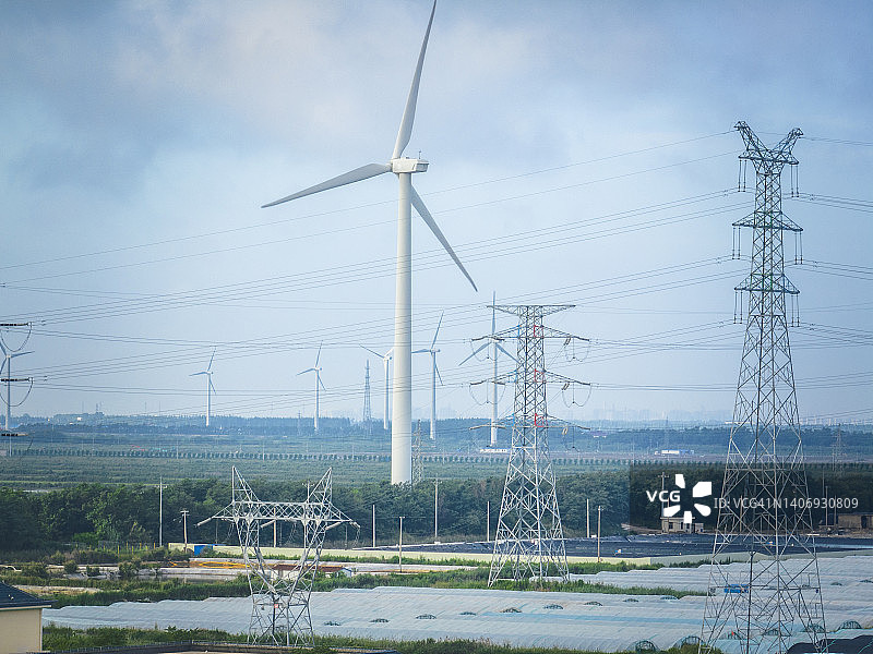 高压塔传输由风力涡轮机产生的绿色能源图片素材