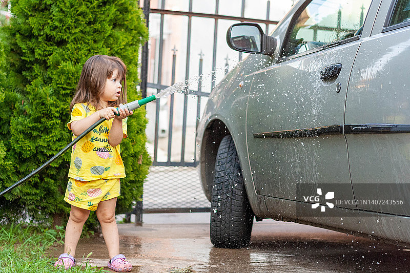 这个小女孩正在洗她父母的车。图片素材