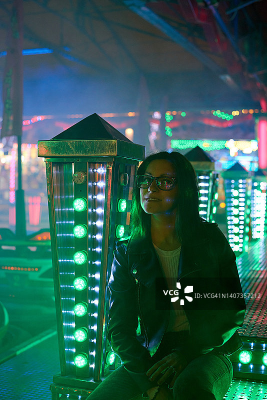 一个戴着眼镜的黑发女子坐在游乐场的景点上图片素材
