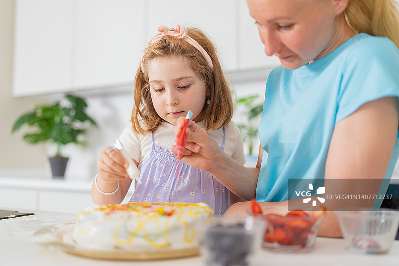 小女孩在家和妈妈一起在厨房里做蛋糕图片素材