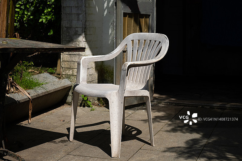 一把又旧又脏的白色塑料椅子。污染环境的观念，过度消费主义。图片素材