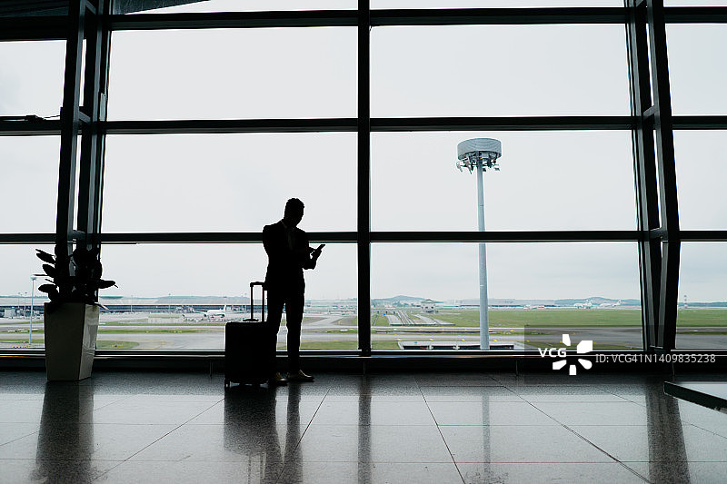 一位商务旅行者在机场使用智能手机的剪影图片素材