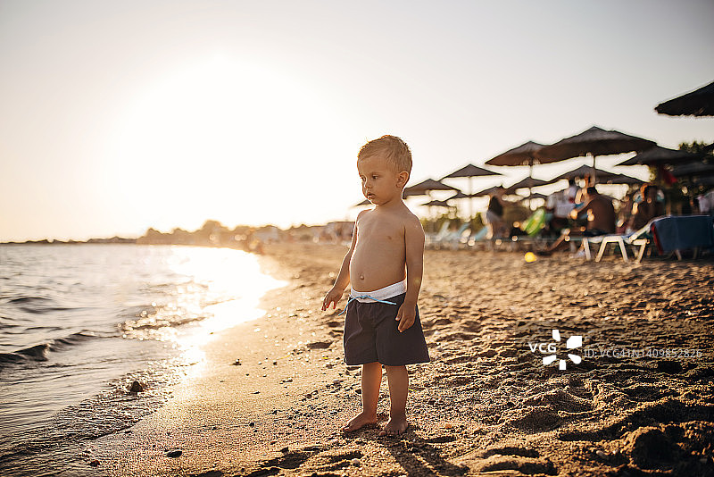 小男孩站在海滩上看日落图片素材