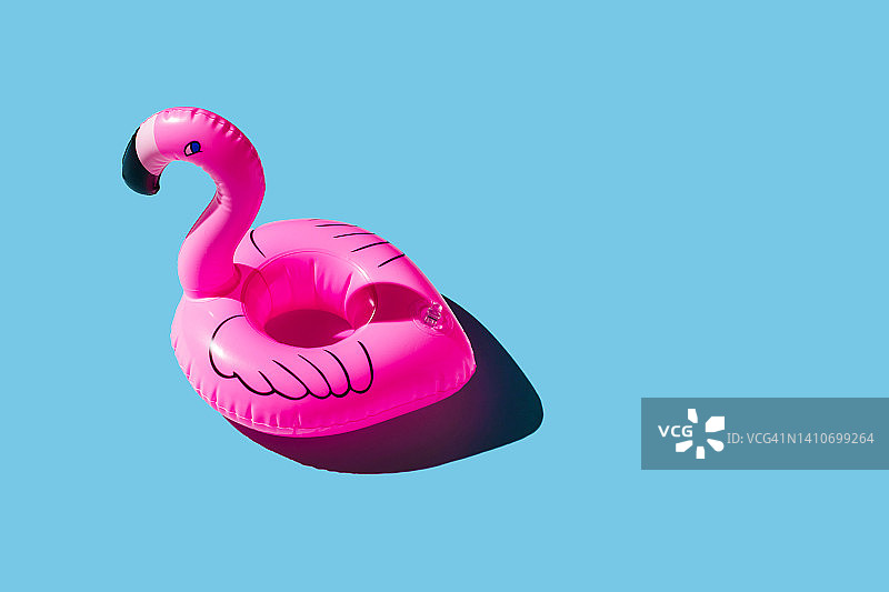 蓝色背景的粉红色充气火烈鸟。暑假的概念。图片素材