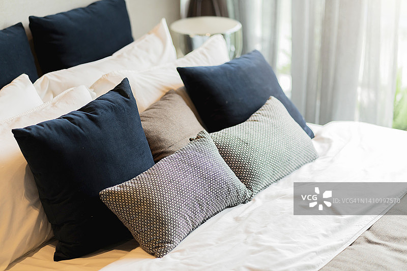 卧室室内设计近观，家居室内概念软枕布置在卧室大尺寸白色毛毯床垫上，以白色窗帘为背景的家居温馨家居室内理念图片素材