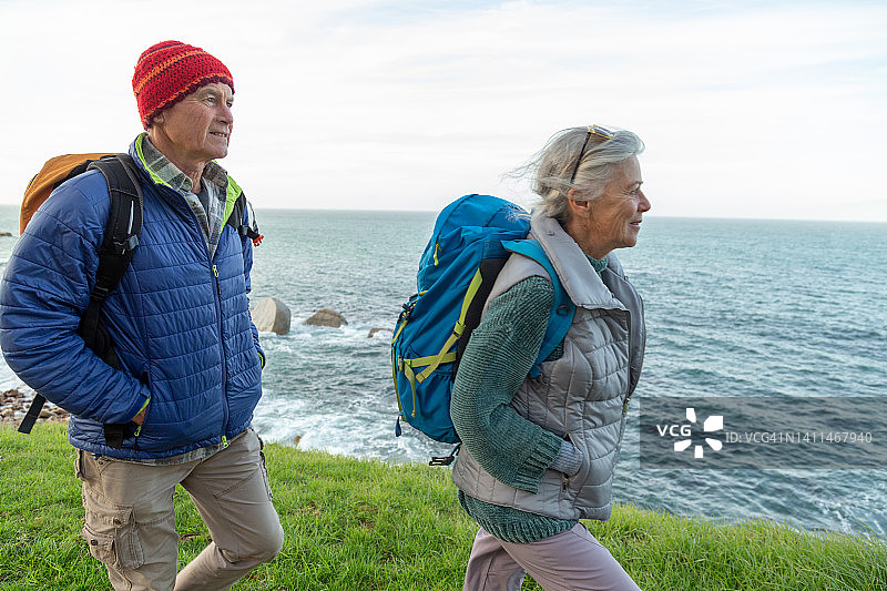 一对老夫妇沿着海岸徒步旅行图片素材