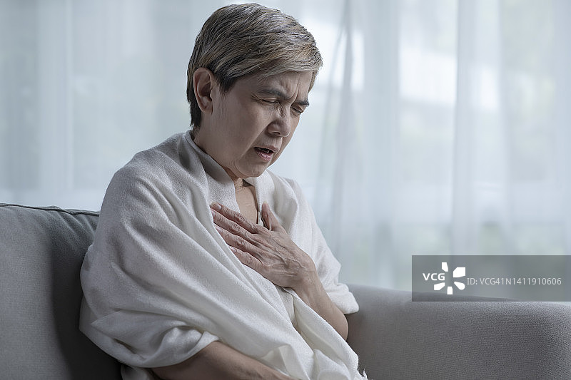 一名亚洲老年妇女独自在家时心脏病发作。图片素材