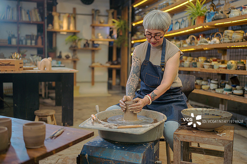 高级女艺术家在陶轮上制作陶碗。图片素材