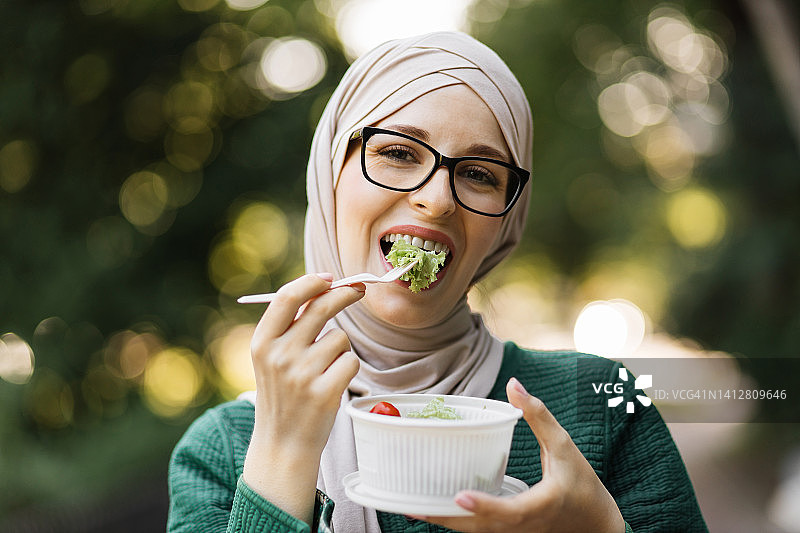 特写肖像穆斯林商业妇女拿着蔬菜沙拉在一个塑料碗图片素材