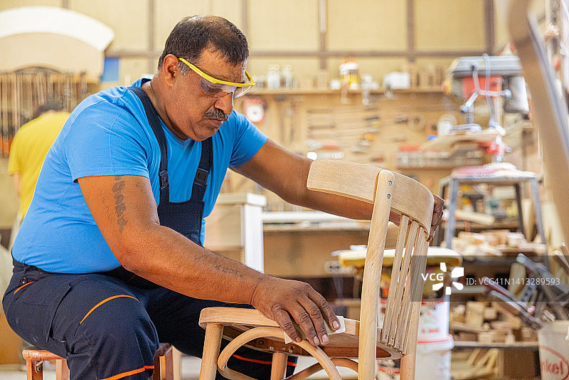 印度木匠独自在他的车间工作。他戴着安全眼镜图片素材