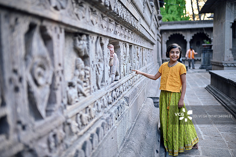 一个可爱的小女孩在一座古老的寺庙里观察石雕图片素材