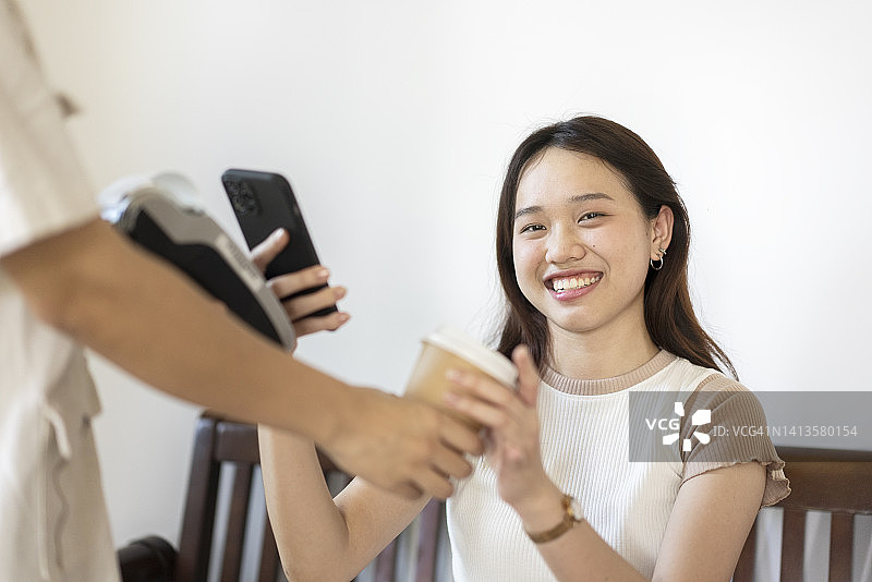 积极情绪亚洲青少年Z世代使用智能手机扫描和交易非接触式支付购买外卖咖啡图片素材
