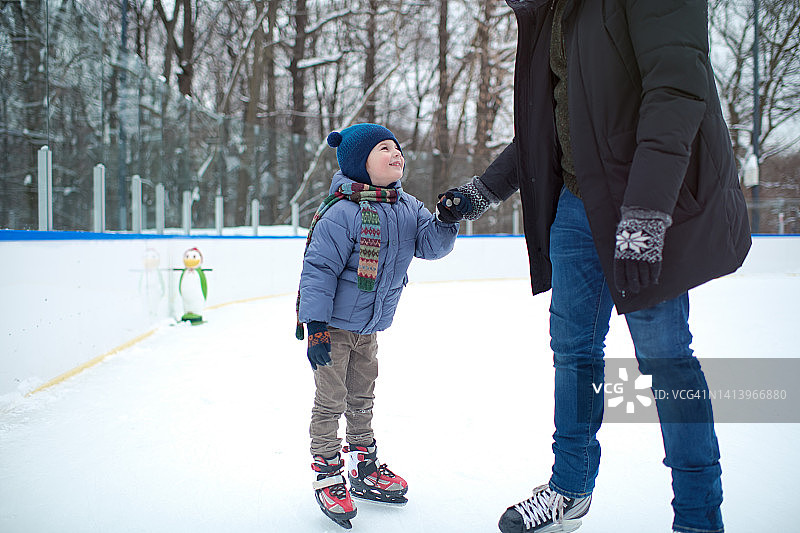父亲在冬天教他的小男孩在户外滑冰图片素材