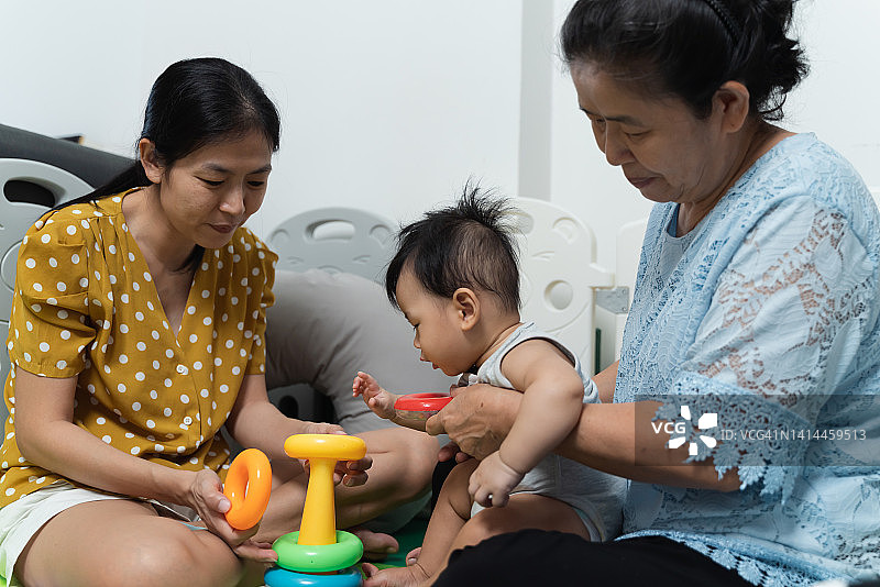 亚洲家庭一起在家里玩五颜六色的玩具。图片素材