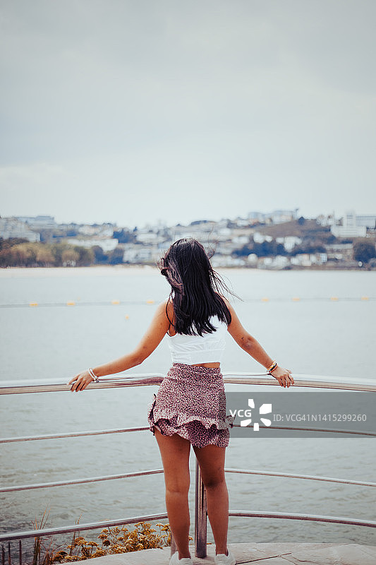 年轻漂亮的拉丁女郎，穿着休闲的衣服，在夏天眺望着西班牙的大海图片素材