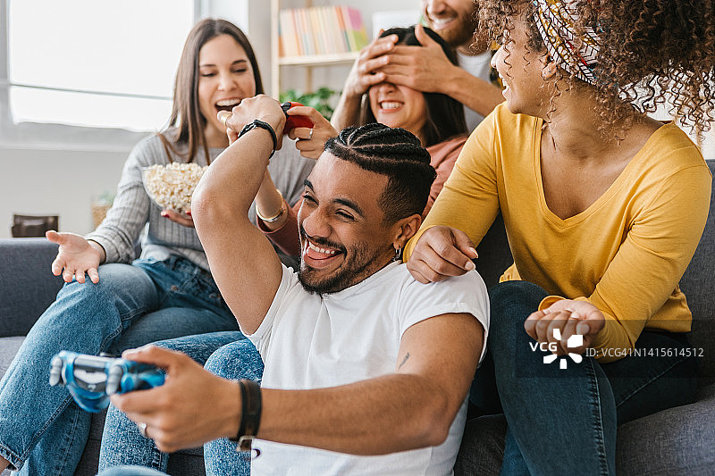 兴奋的多种族年轻朋友在家里一起玩电子游戏，玩得很开心图片素材