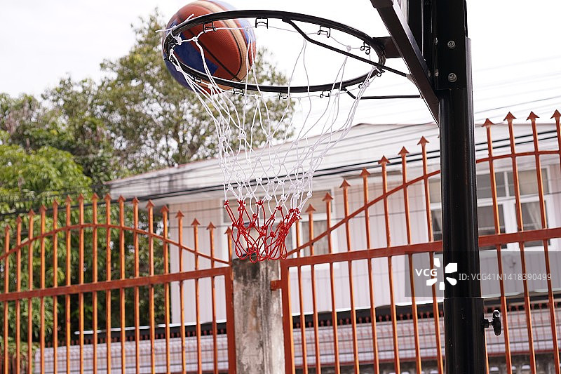 体育:篮球射入篮筐的瞬间，特写镜头，没有人的运动装备。图片素材