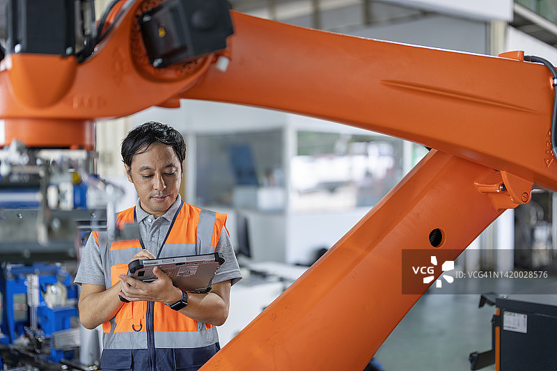 日本工程师在工厂安装过程中检查机器人协同输送系统。图片素材