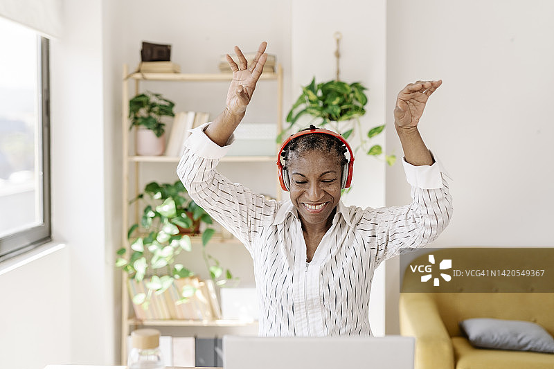 快乐女人戴着无线耳机在家里跳舞图片素材